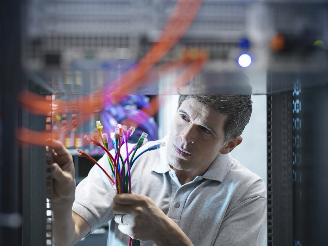 This technician in a data center is wondering where all the cables go.